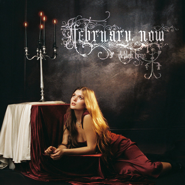 February, now single cover — Delilah Brao in red velvet beside a candelabra under engraved silver lettering